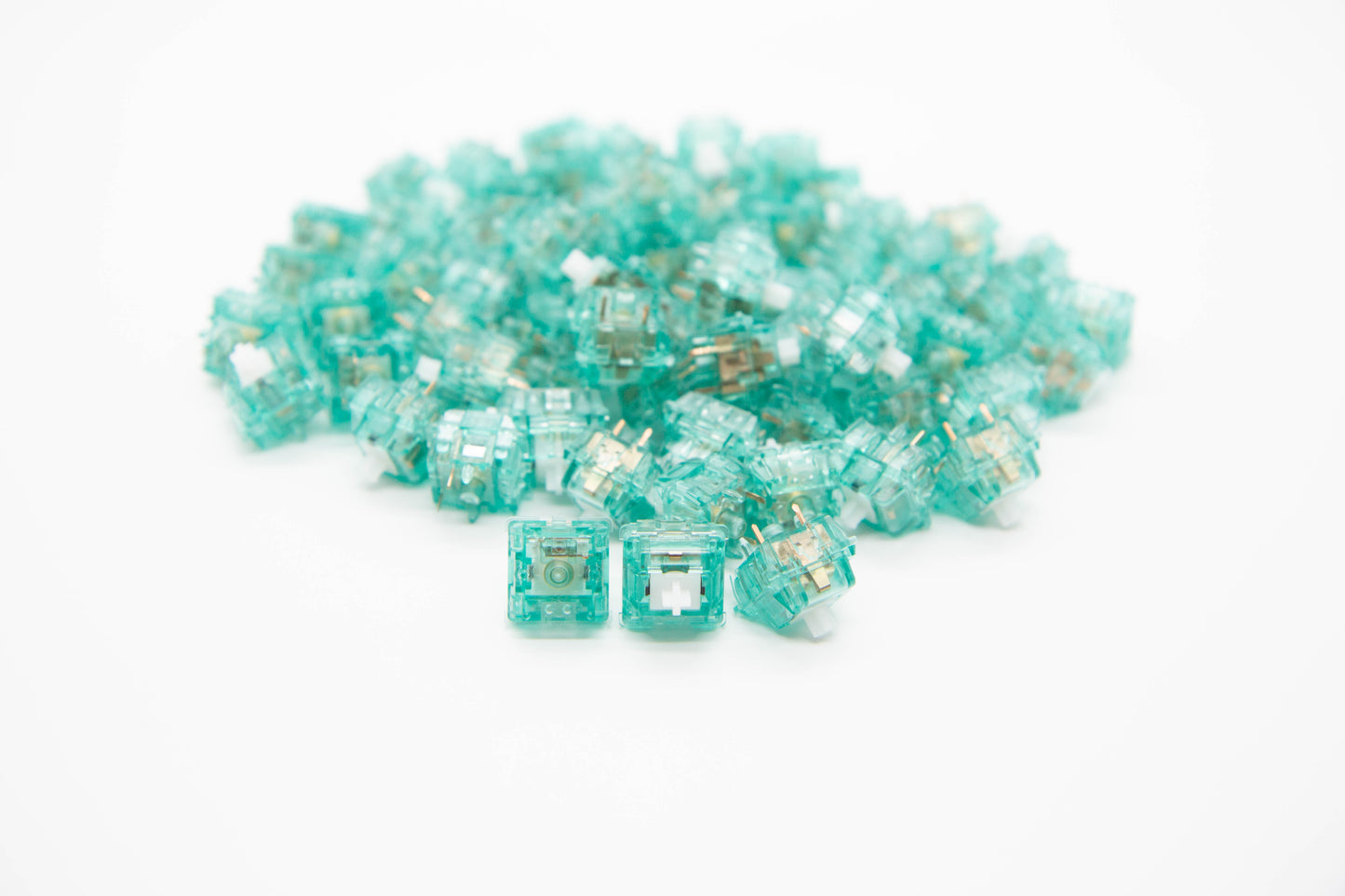 Close-up shot of a pile of Silent T1 mechanical keyboard switches featuring teal transparent housing and clear, white stems