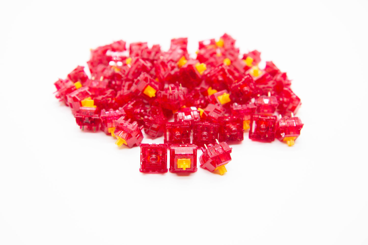 Close-up shot of a pile of Tecsee Ruby V2 mechanical keyboard switches featuring bright red transparent housing and yellow stems