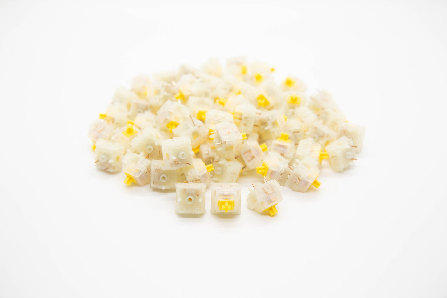 Close-up shot of a pile of Gateron Cap-Milky V2 mechanical keyboard switches featuring white housing and yellow stems