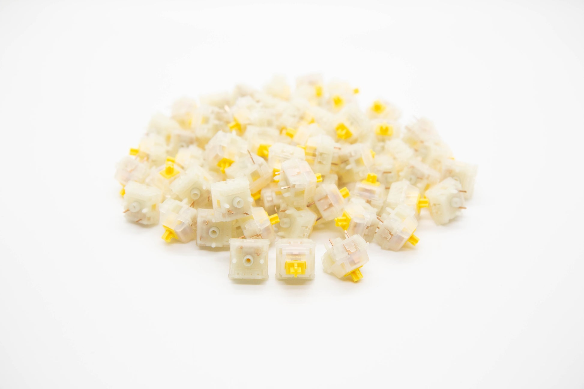 Close-up shot of a pile of Gateron Cap-Milky V2 mechanical keyboard switches featuring white housing and yellow stems