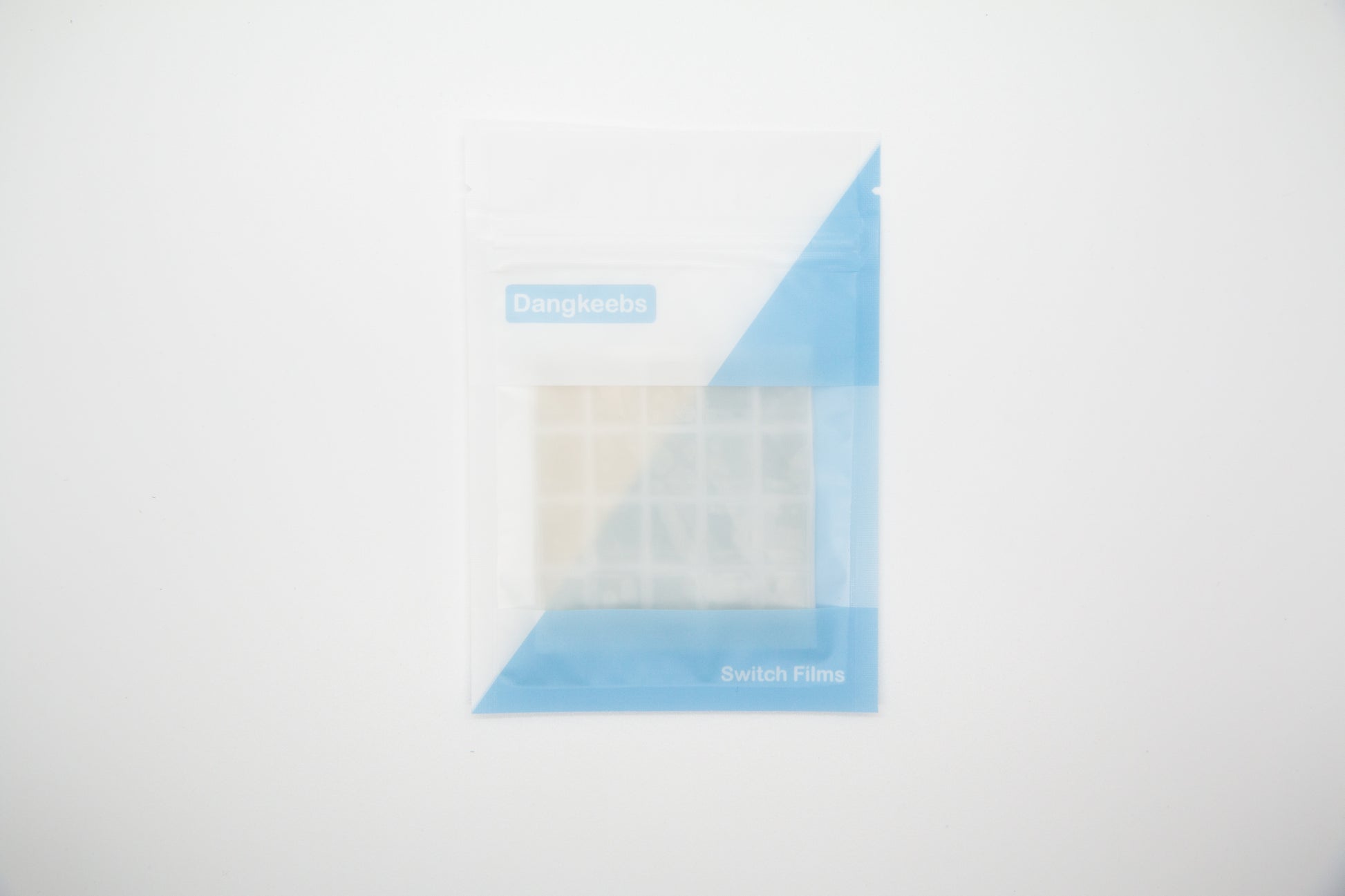 Overhead shot of silicone blend mechanical keyboard switch films in white and blue packaging pouch on a white background