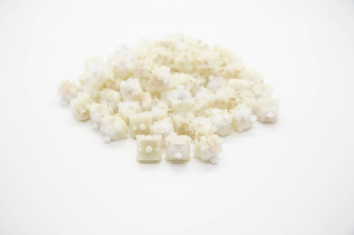 Close-up shot of a pile of Gateron Milky Clear mechanical keyboard switches featuring white housing and clear stems