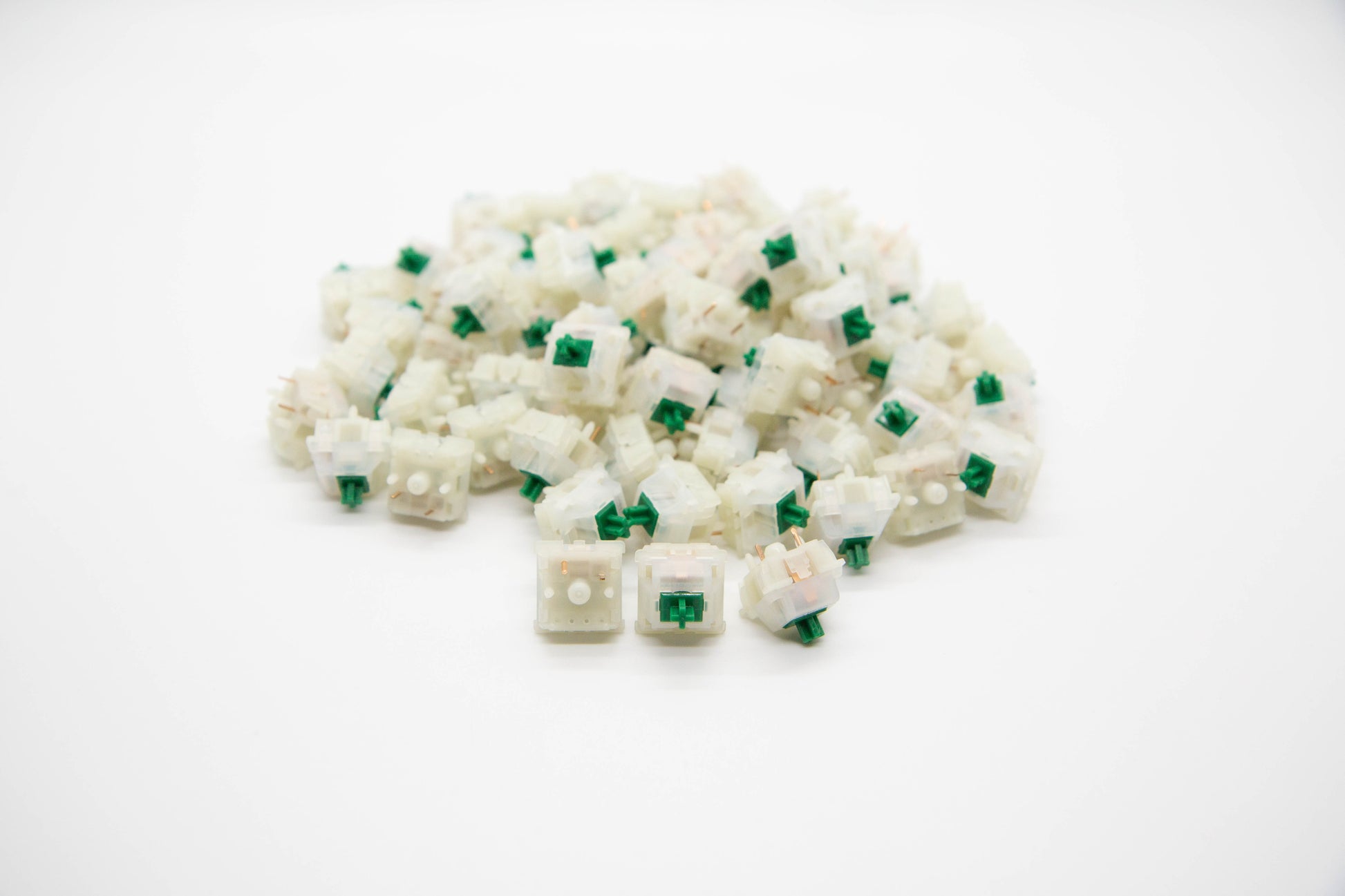 Close-up shot of a pile of Gateron Milky Green mechanical keyboard switches featuring white housing and green stems