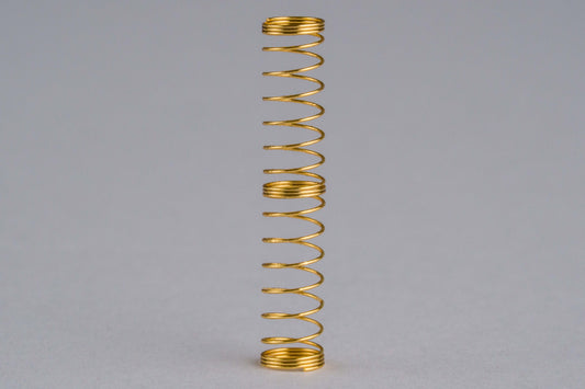 Close-up shot of a single 68g dual stage gold plated mechanical keyboard spring on a grey background